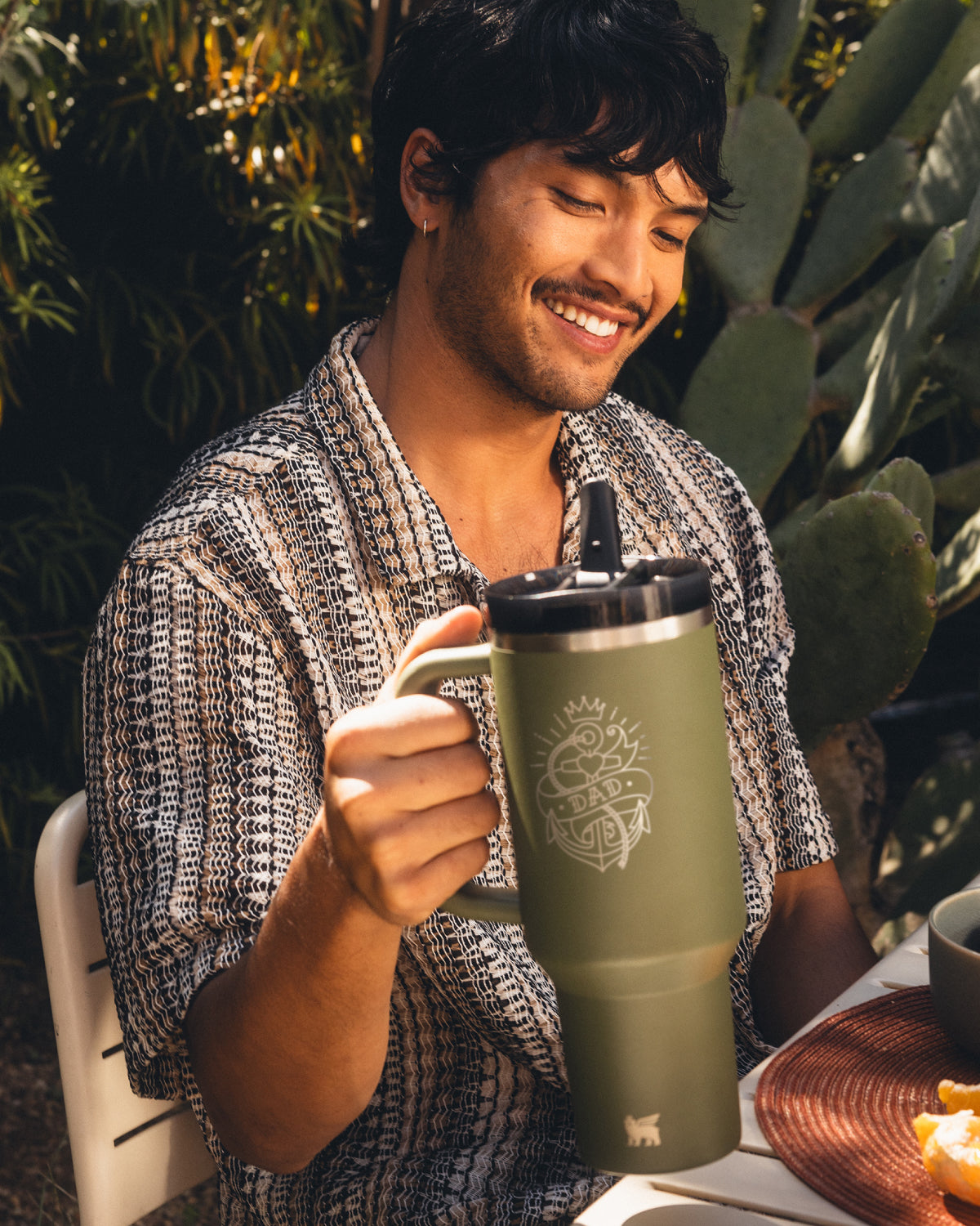 Man sitting at table holding custom engraved father's day tumbler