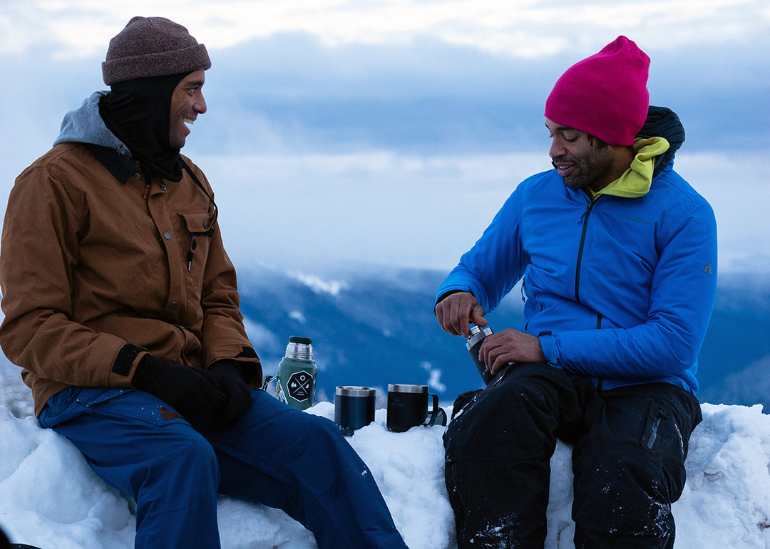 Elijah and Adam enjoy beverages in their Stanley camp mugs overlooking a mountain ridgeline.