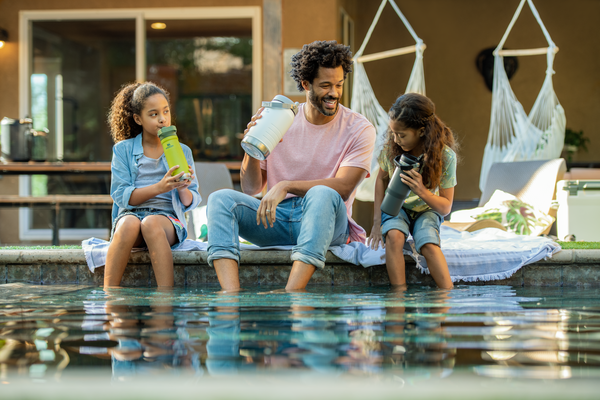 Father with his two daughters sitting poolside with their insulated Stanley IceFlow™ Flip Straw drinkware.