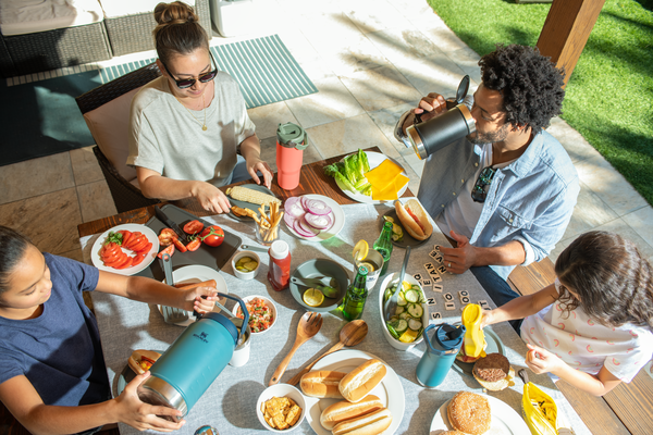 Mother with family enjoying a backyard picnic with colorful drinkware from Stanle's IceFlow™ Flip Straw Collection.