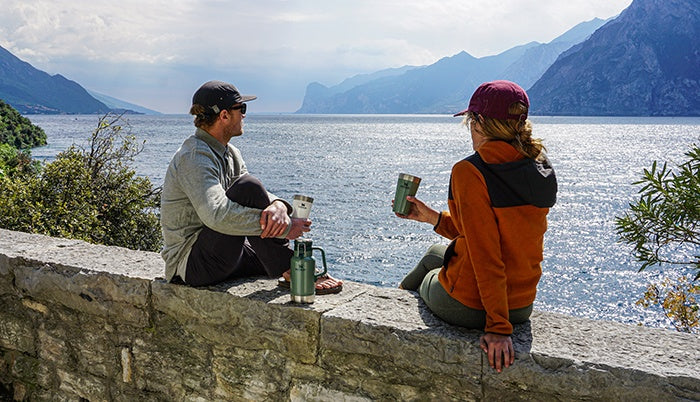 Man and woman overlooking the Mediterranean and holidng their Adventure Beer Pints.
