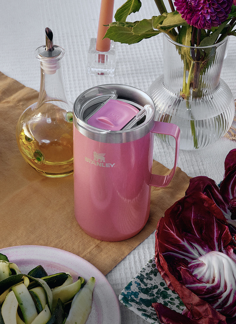 Pink Stanley mug with a handle on a dining table set for a meal