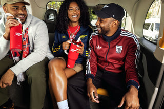 People In Car Wearing Arsenal Gear and Drinking From Stanley Arsenal Collab Water Bottles